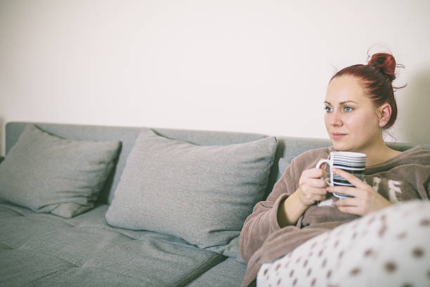 istock Young woman drinking coffee in her bed wearing pajamas 629867366