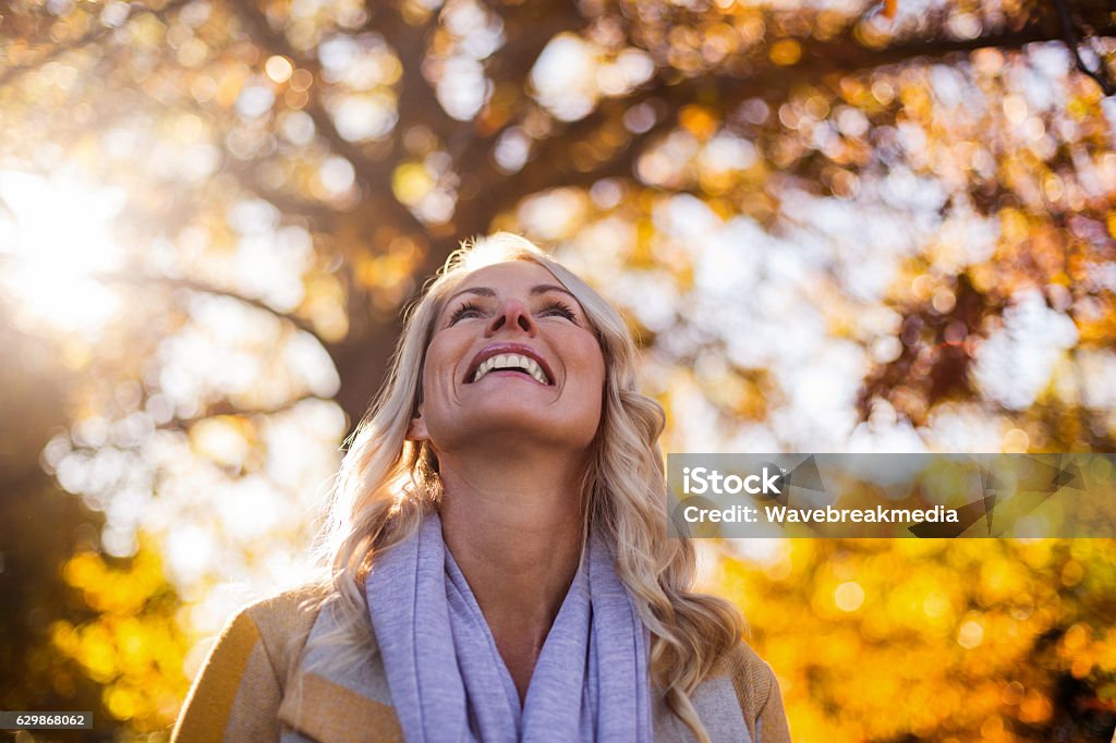 Lächelnde Frau schaut gegen Bäume - Lizenzfrei Herbst Stock-Foto