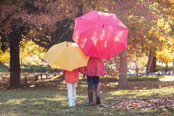 istock Mother and daughter with umbrella at park 629868452