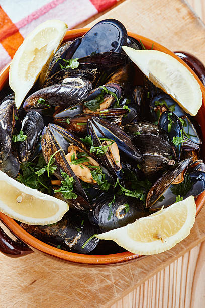 istock Mussels in a pot, lemons, tablecloth on wooden table 629940798