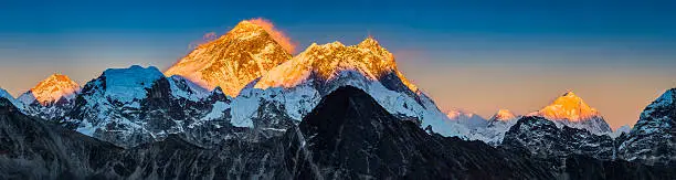 Golden sunset light illuminating the iconic pyramid peak of Mt. Everest (8848m) and the summits of Nuptse (7861m), Lhotse (8516m) and Makalu (8463m) in this vibrant Himalaya mountain panorama deep in the Sagarmatha National Park of Nepal, a UNESCO World Heritage Site.
