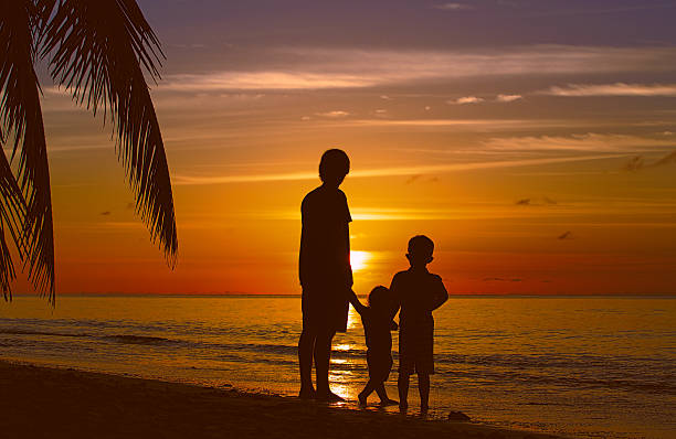 istock father and two kids walking on beach at sunset 629942014