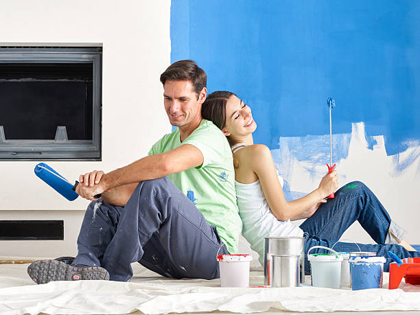 istock Couple sitting back to back with roller brushes in hand 629942488
