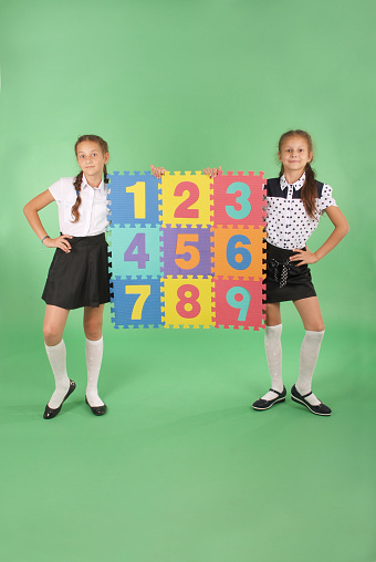 Two school girls hold color board with the number one, two, three, four, five, six, seven, eight, nine on green