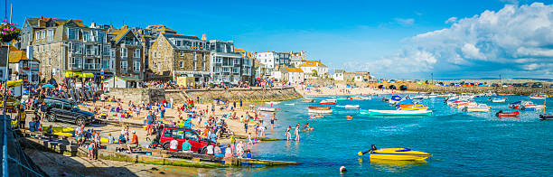 Crowds of tourists on harbour beach panorama St Ives Cornwall Crowds of holiday makers, day trippers and tourists enjoying the summer sunshine on the popular harbour beach of St. Ives, Cornwall. st ives cornwall stock pictures, royalty-free photos & images