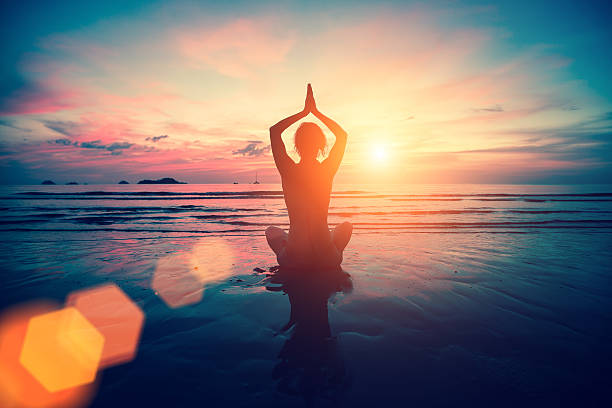 istock Silhouette young woman practicing yoga on the beach at sunset. 629953456