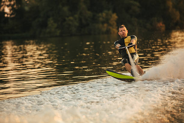 istock Man riding wakeboard on wave of motorboat 629956072