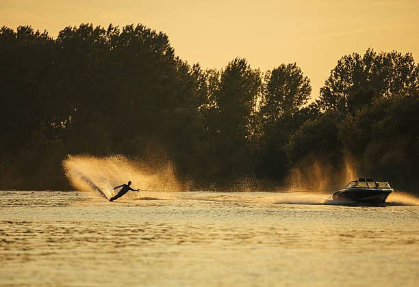 человек вейкбординг на озере за лодкой - wakeboarding waterskiing water ski sunset стоковые фото и изображения
