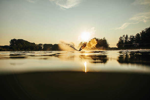 日没時に湖でスキーをするウェイクボーダー - wakeboarding waterskiing water ski sunset ストックフォトと画像