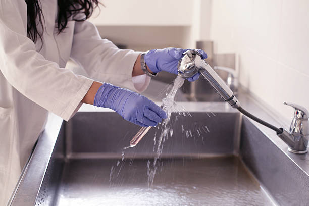 Woman scientist washing testing tubes under water
