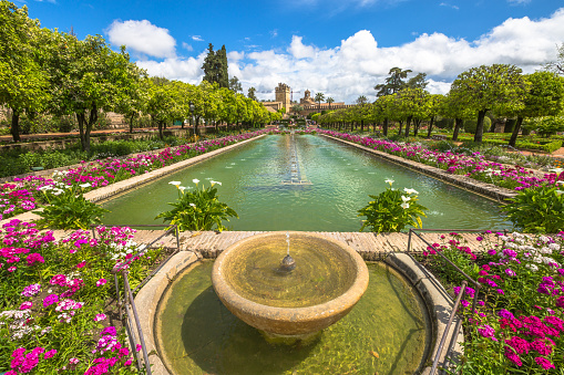 Cordoba, Andalusia, Spain - April 20, 2016: The popular gardens with fountains of Alcazar de los Reyes Cristianos, a popular tourist attraction of Cordoba, Andalusia, Spain. Unesco Heritage Site.