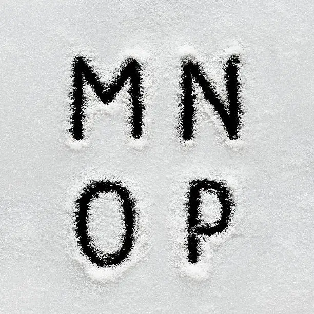 Photo of Winter alphabet, symbols and numbers hand written on snow.