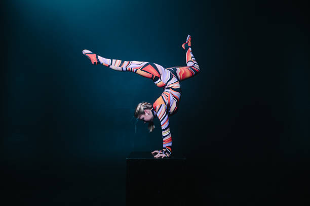 Flexible circus acrobat doing equilibre balance handstand on a cube. Young flexible blonde circus acrobat posing in studio in costume. Doing equilibre balance handstand on a cube. Copy space text. acrobat stock pictures, royalty-free photos & images