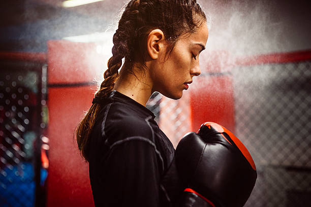 Boxing is her Passion Female boxer in a boxing ring training. condensation, heat and sweat. Low lighting with a spot light in the background. Very real and gritty boxing stock pictures, royalty-free photos & images