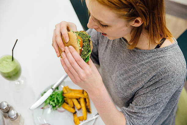 tucking in to a healthy veggie burger - cafe buns eating bildbanksfoton och bilder