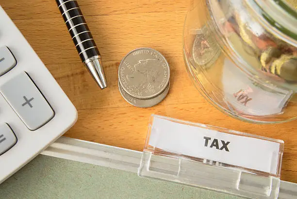 Tax file with calculator, pen, coins and glass jar