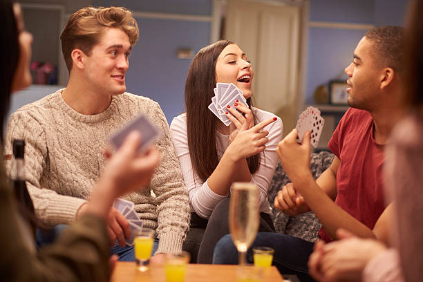 card games a group of young friends sit on the sofa and play a game of cards . There are drinks on the table too where it could be a drinking game . **Cards have been modified to remove identifying designs** friends playing cards stock pictures, royalty-free photos & images