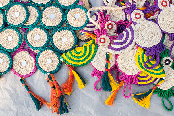 A vibrant assortment of handcrafted items, including coasters and small mats, meticulously made from natural fiber like jute. Displayed on a glass shelf, these colourful and textured products represent the rich artisanal traditions, eco-friendly craftsmanship, and cultural heritage of Bangladesh and South Asia.