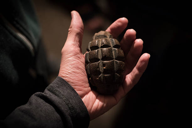 vieille grenade tenue dans la paume ouverte de la main - grenade à main photos et images de collection