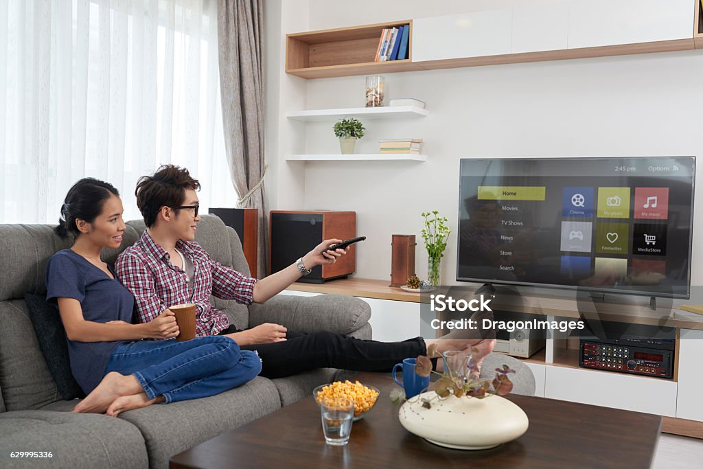 Chossing channel Asian couple choosing channel on their smart tv Watching TV Stock Photo