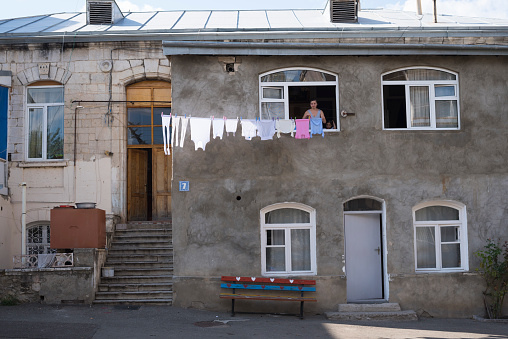 Stepanakert, Nagorno-Karabakh, Azerbaijan - September 22, 2016: A woman, a little girl beside her, hangs laundry to dry outside their home in Stepanakert, the capital of Nagorno-Karabakh.