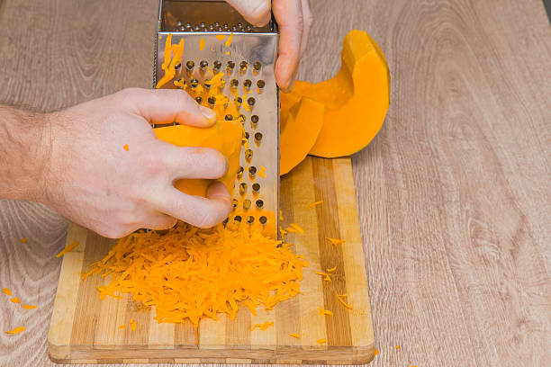 istock Man's hands with a grater grate the pumpkin. Healthy eating. 630007882