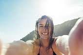 young woman taking a POV Selfie photograph on Porthcurno beach.
