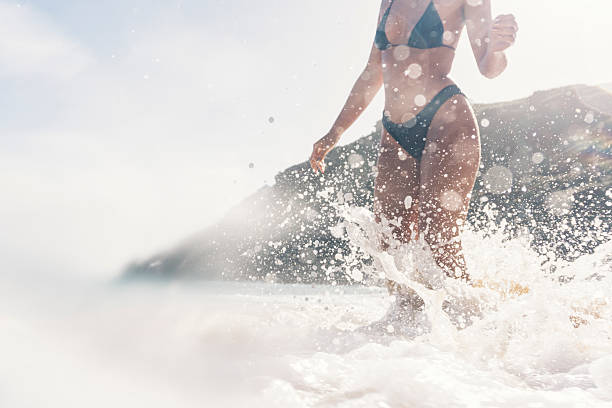 istock young woman playing in the waves, Porthcurno Beach, Cornwall 630017480