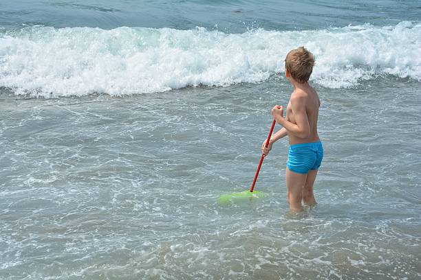 少年は海で漁網を持って立っている - kescher ストックフォトと画像