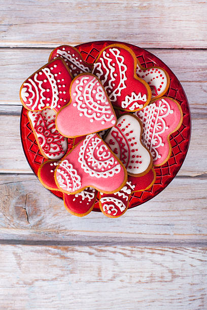 Valentine's background with heart shaped gingerbread cookies. Valentine's background with Glazed heart shaped gingerbread cookies on rustic wooden table. Used gingerbread cookies home-handedly made it from me. They are unique pieces and can not be found anywhere. white sugar cookie stock pictures, royalty-free photos & images