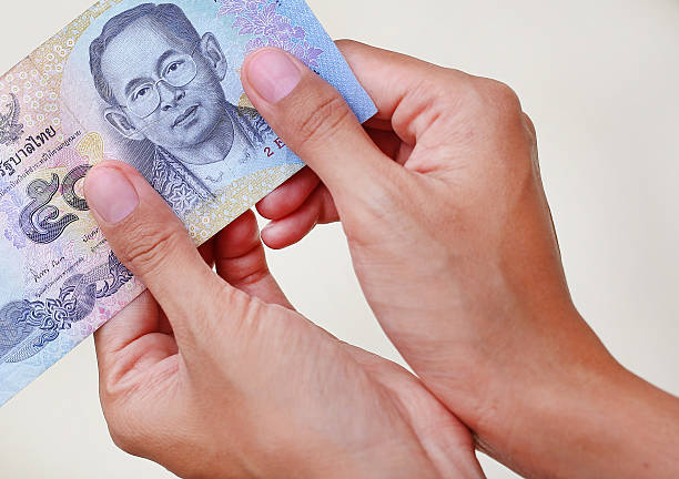 istock Hand giving fifty bath Thai money on white background 630054060