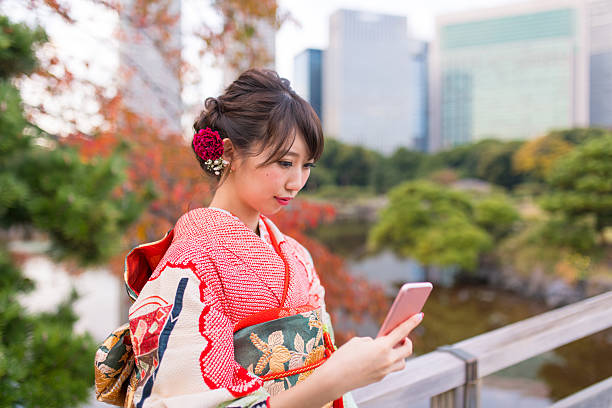 chica joven furisode lookin en la pantalla en el teléfono inteligente - japanese ethnicity seijin no hi people outdoors fotografías e imágenes de stock