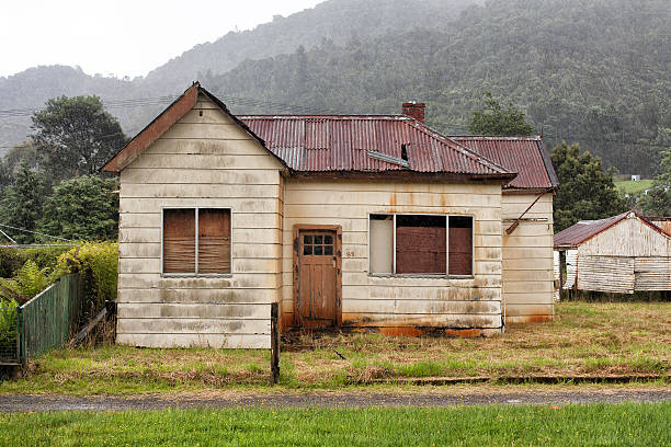 Abandoned old timber home Old abandoned weatherboard home and shed in Queenstown, TasmaniaOld abandoned weatherboard home and shed in Queenstown, Tasmania drab stock pictures, royalty-free photos & images