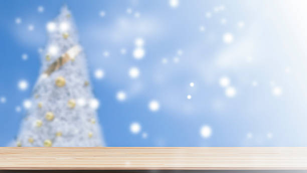 Wood table top on blur Christmas tree in snowfall background stock photo