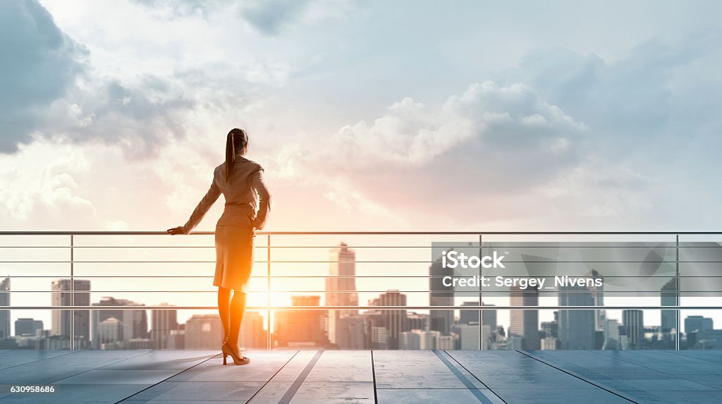 Businesswoman on building roof . Mixed media Young business lady on top of building against cityscape Opportunity Stock Photo