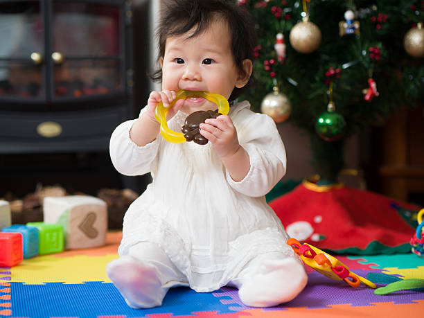 Cute little baby with teether in comfortable crib at home