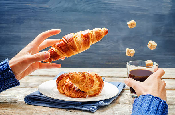 istock Male hand with flying croissant and coffee 631181826