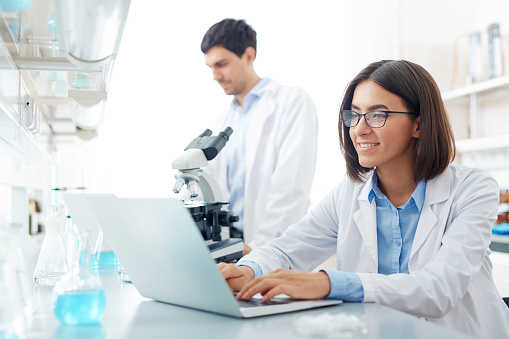 Lab worker sitting in front of laptop and searching for data for new experiment