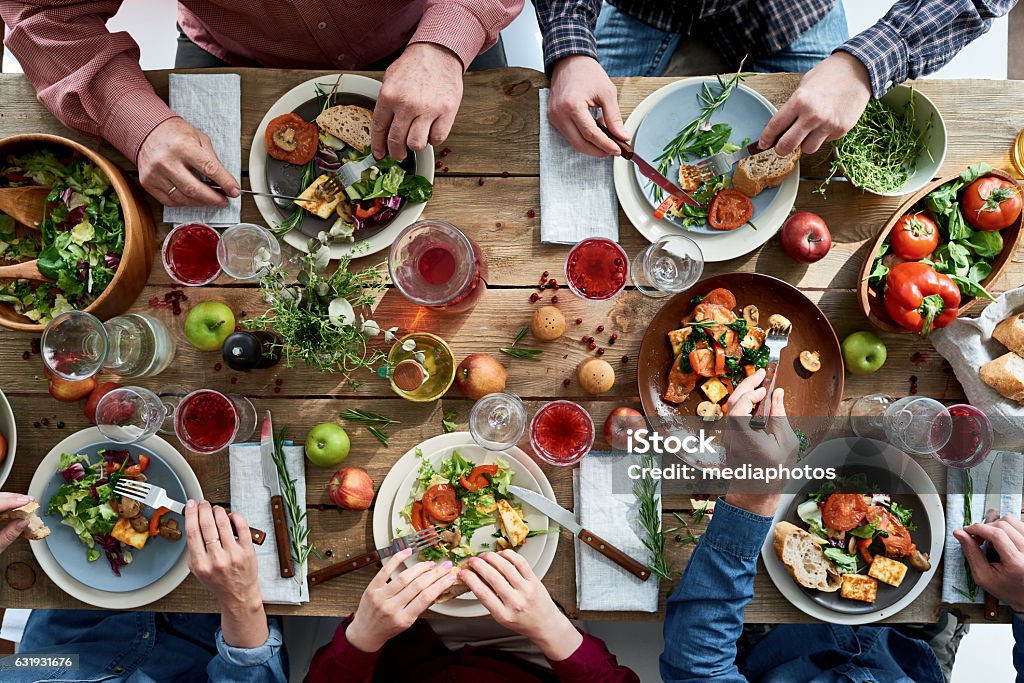 People having dinner Directly above view of unrecognizable friends eating together at diner party Dining Table Stock Photo