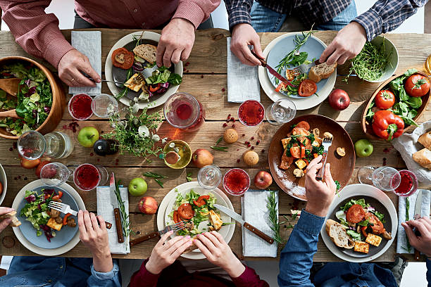 Directly above view of unrecognizable friends eating together at diner party