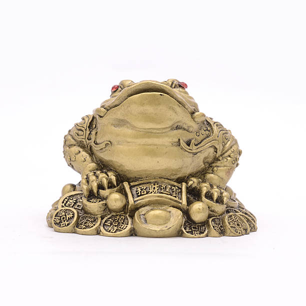istock golden frog figurine on coins isolated on white 631931926