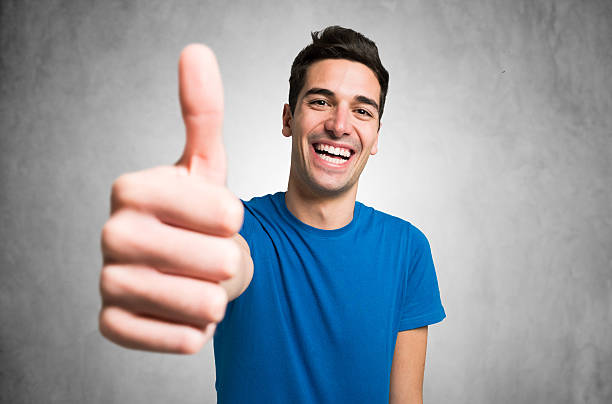 heureux homme souriant, donnant thumbs up - expressive hands photos et images de collection