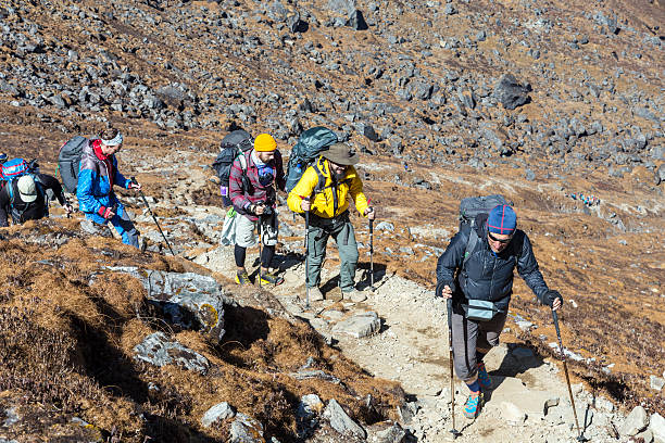 istock Large Diverse Group of People walking up on rocky Trail 633685442