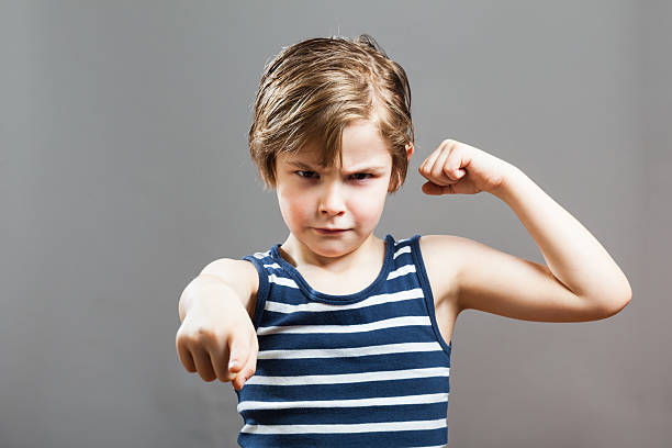 istock Portrait Of Boy Flexing Muscles Against Gray Background 635101263