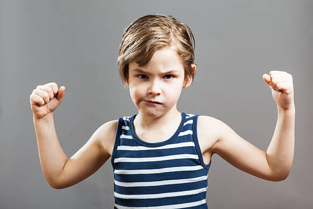 istock Portrait Of Boy Flexing Muscles Against Gray Background 635101267