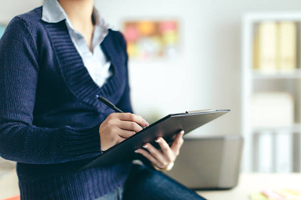 Business woman looking over papers Young woman in office petition stock pictures, royalty-free photos & images