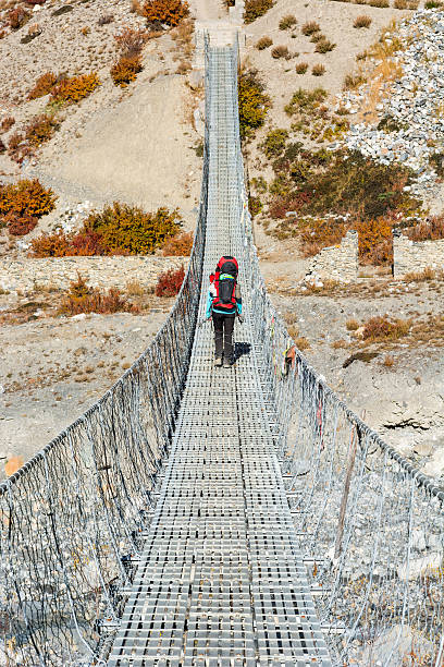 istock Trekker crossing metal suspension bridge. 635479188
