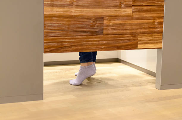 Woman standing on tip toe in a changing room Woman standing on tip toe in a changing room at a store as she tries on clothes, view of her feet under the wooden door fitting room doors stock pictures, royalty-free photos & images
