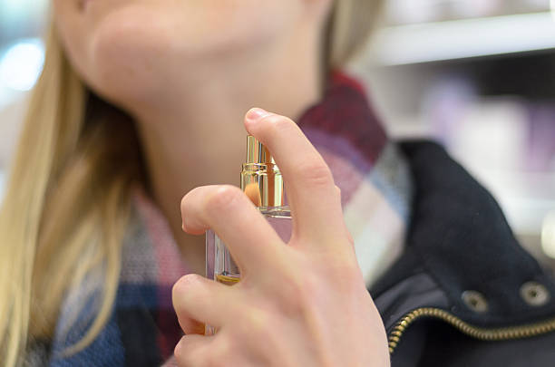 istock Young woman spraying her neck with perfume 635671220