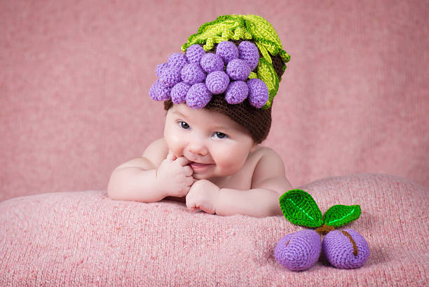 Newborn baby a knitted cap in the form of grapes. stock photo